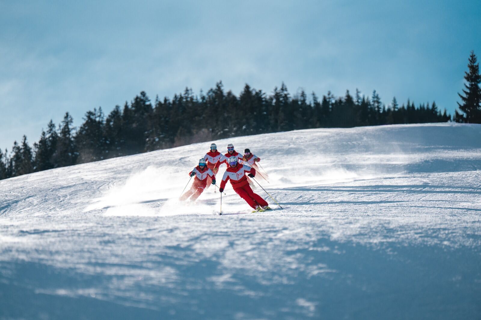 Skileraren van Skischule Mösern-Seefeld in rode jassen tijdens een afdaling op een zonnige piste